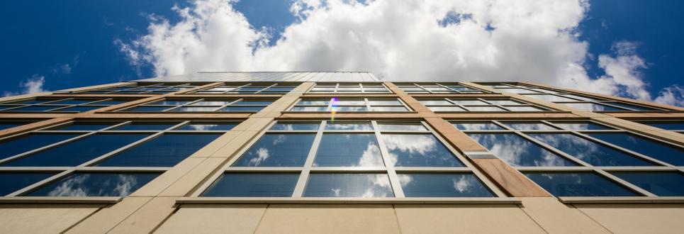 Looking up the side of a building with a blue sky and clouds above